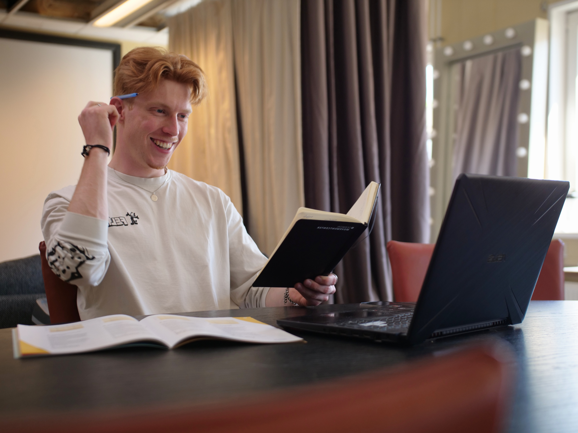 Oprichter van VINK die met een pen achter zijn oor, een notitieboek in zijn hand en een laptop voor zich op tafel heeft liggen, met een lach op zijn gezicht de school contacteerd die nog niet is aangesloten bij VINK, maar wel is aangevraagd door leerling.