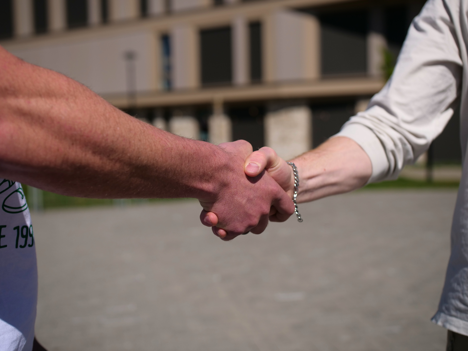 Detailopname van een stevige handdruk tussen twee personen buiten in het daglicht.