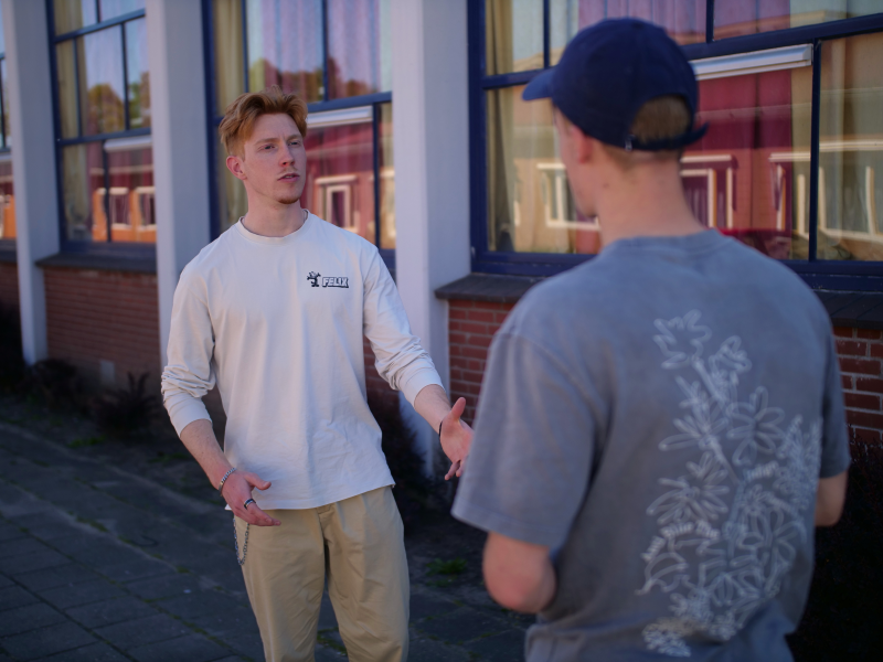 Een gesprek tussen leerling en begeleider buiten op een rustige plek op het schoolplein.