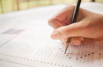 Detailopname van een hand die met potlood een meerkeuzetoets (multiple choice) invult op papier.