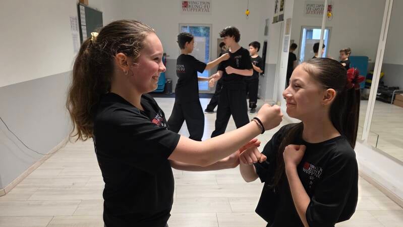 Zwei Mädchen beim Partnertraining mit breitem Lachen, Kampfsport Kinder in Wuppertal