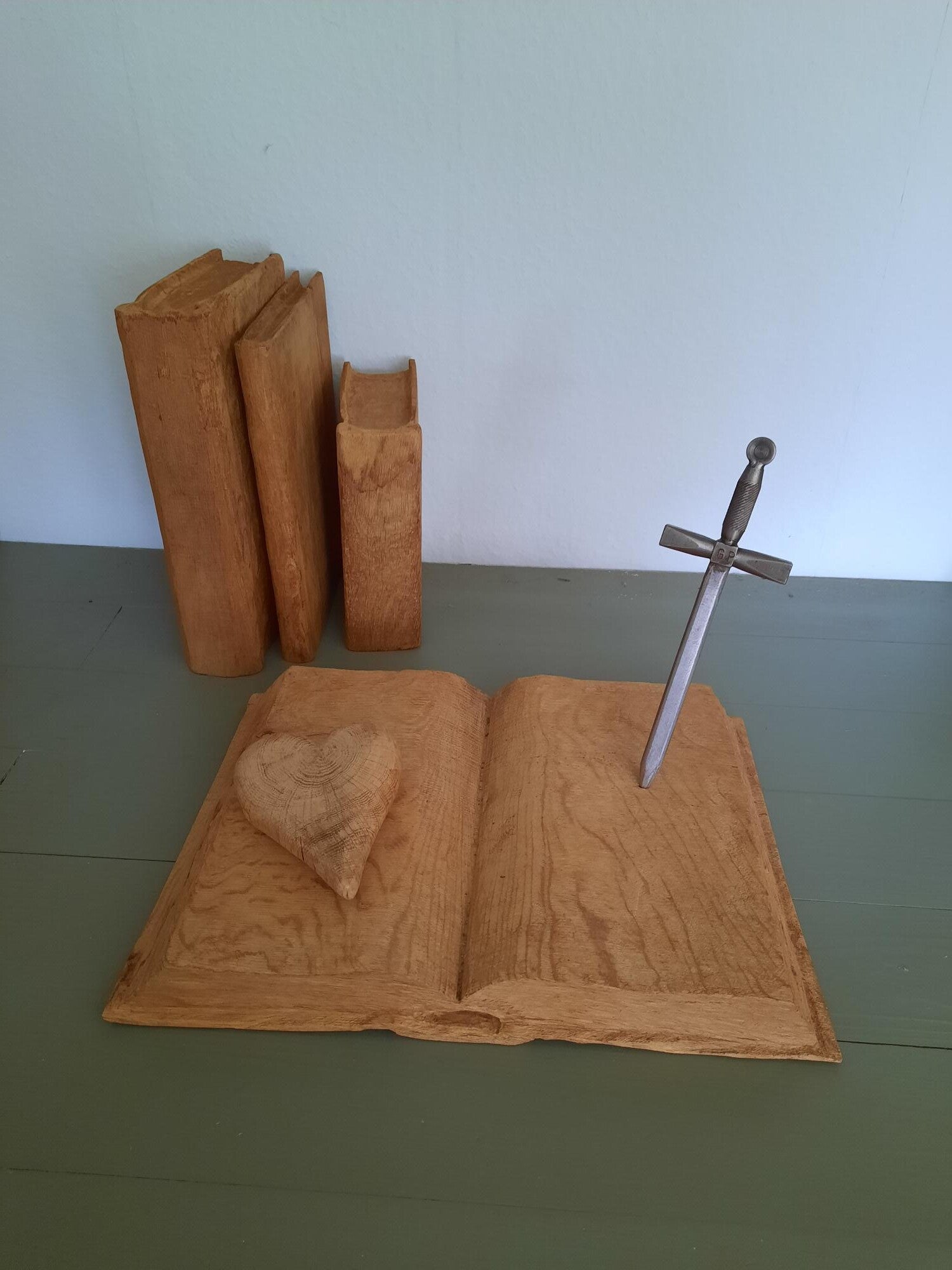 Houtsculptuur van een bijbel met een hart van Gods liefde en een zwaart omdat liefde ook vaak strijd kost