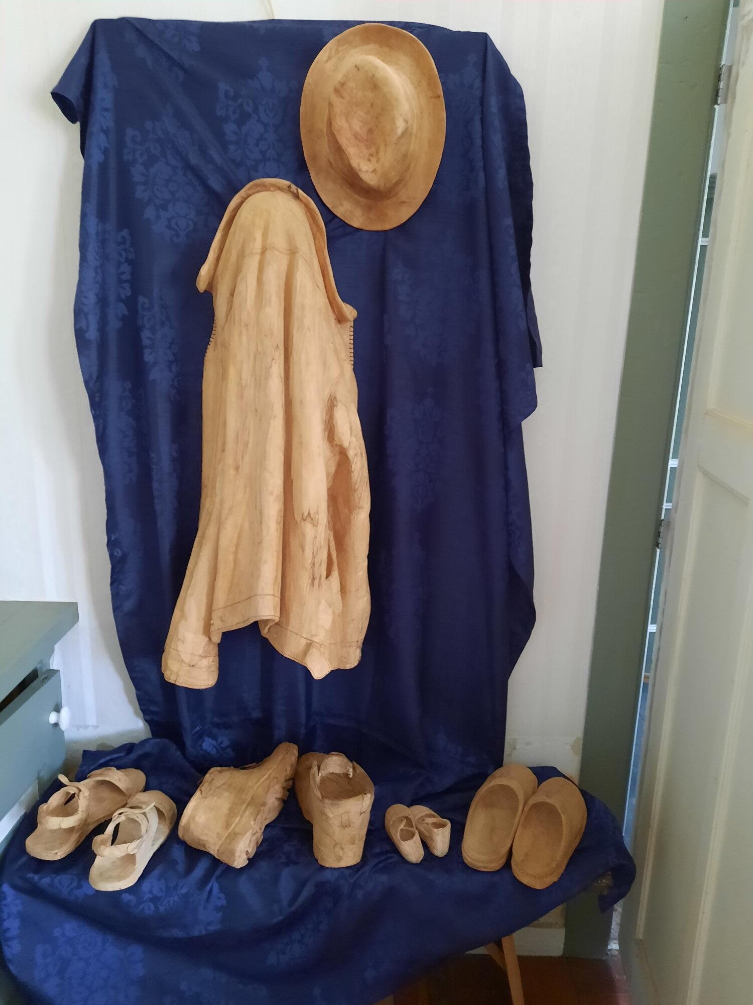 Houtsculptuur van een jas met hoed en schoenen