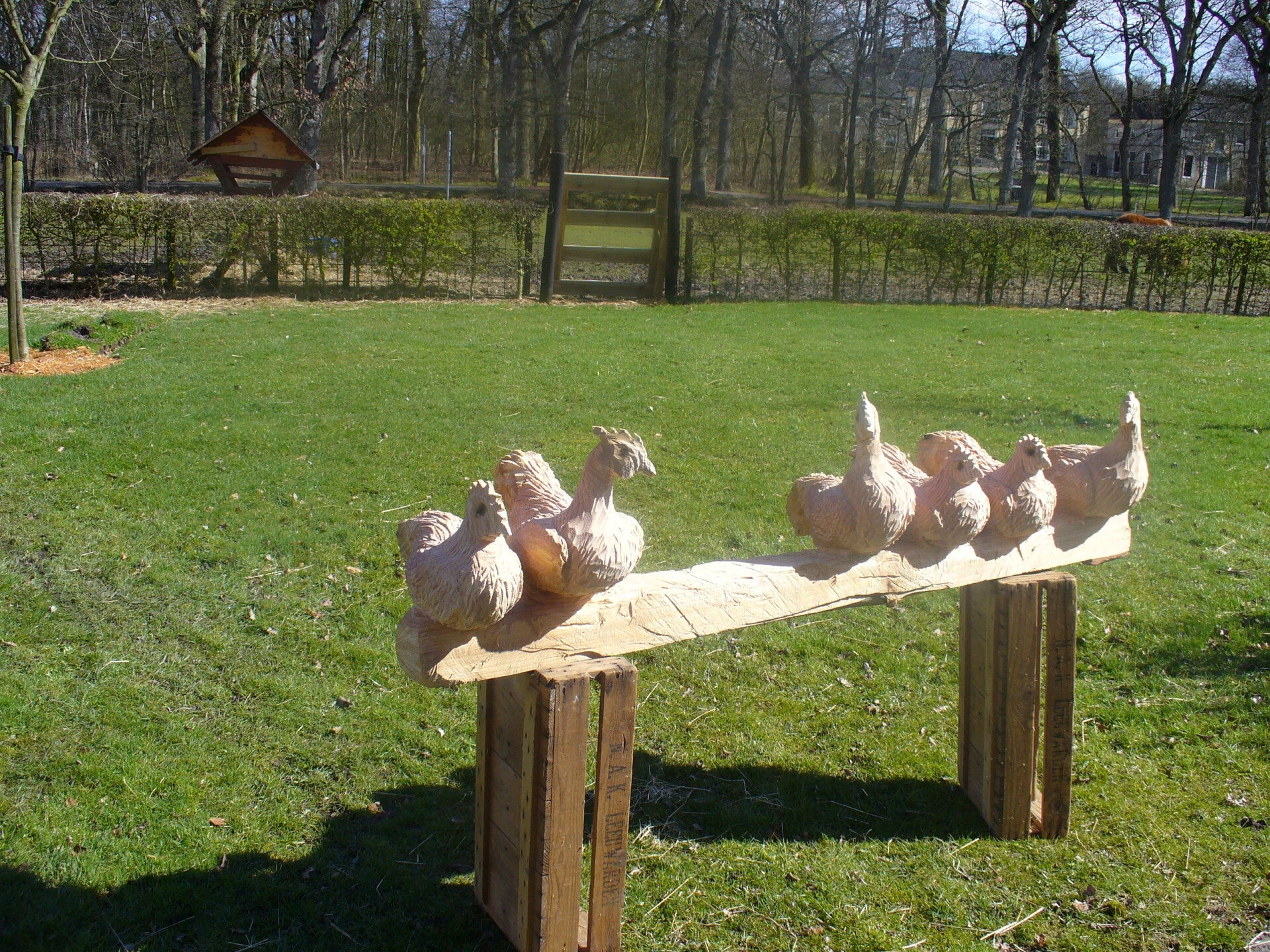 Houtsculptuur van kippen op stok