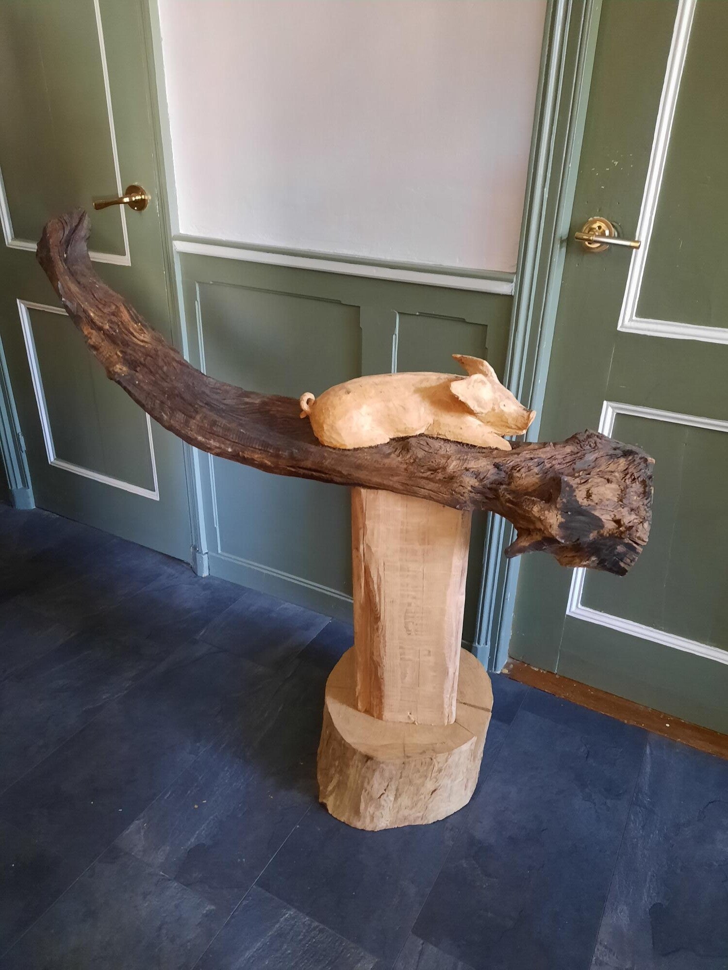 Houtsculptuur van een varken spelend in de modder