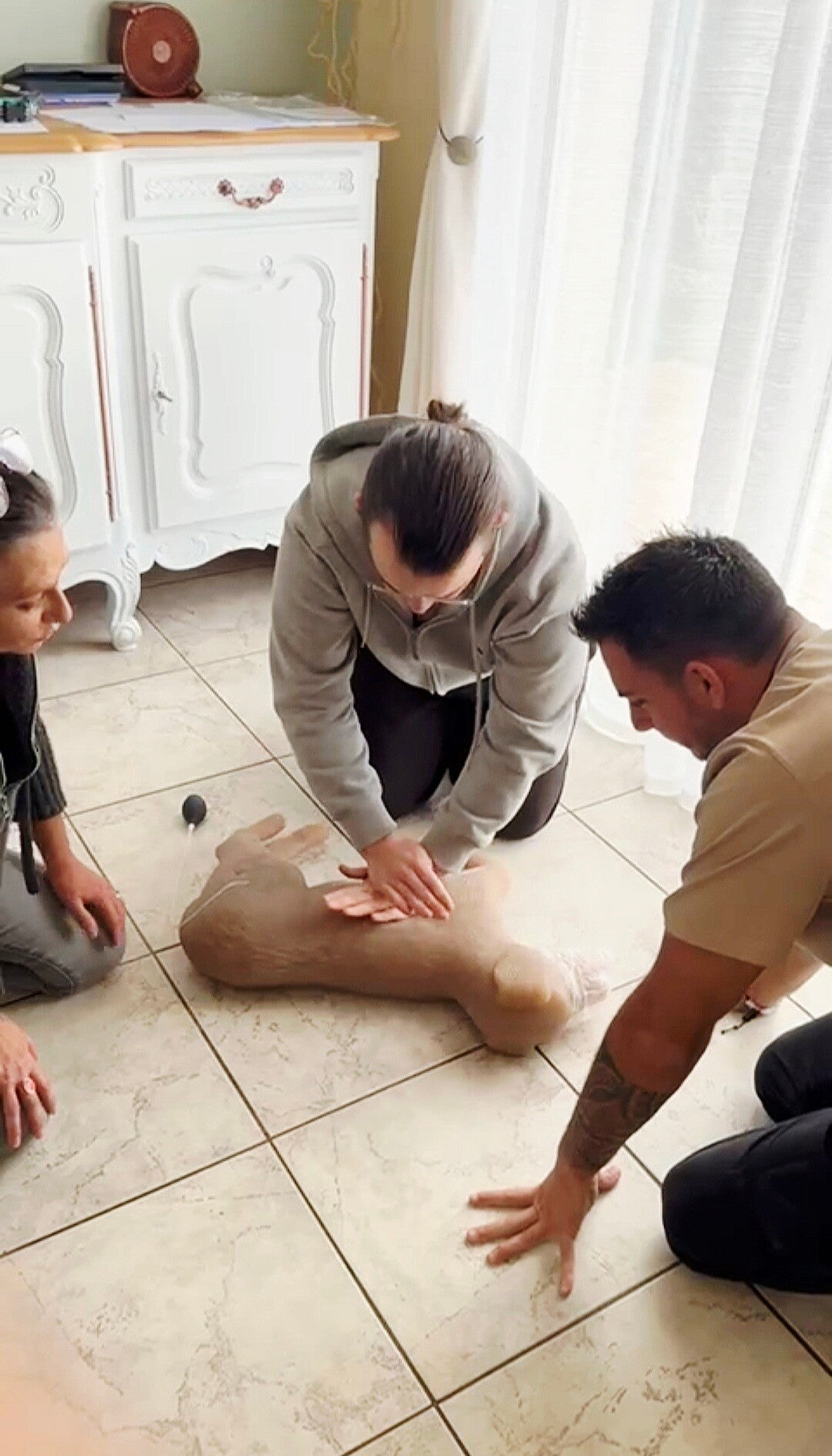 un homme qui s'entraine à faire une réanimation cardio respiratoire sur un mannequin chien et un autre qui attend pour faire le bouche à truffe 