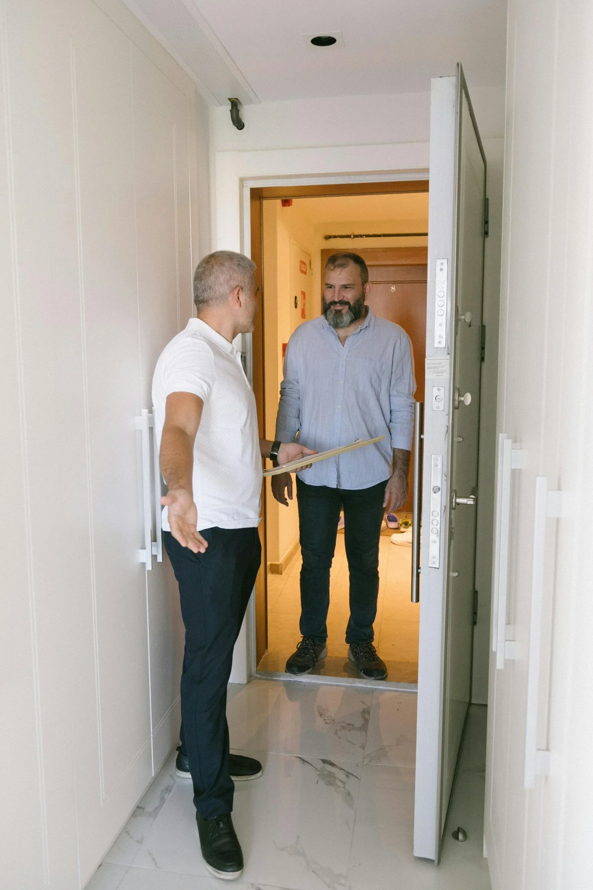 Schlüsseldienst-Monteur spricht mit einem Kunden an einer geöffneten Wohnungstür – professionelle Türöffnung und Hilfe bei Schlossproblemen.