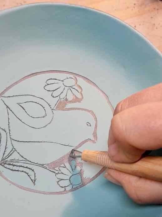 Artisan céramiste à Givet en train de décorer une pièce à l'engobe et sgrafitto
