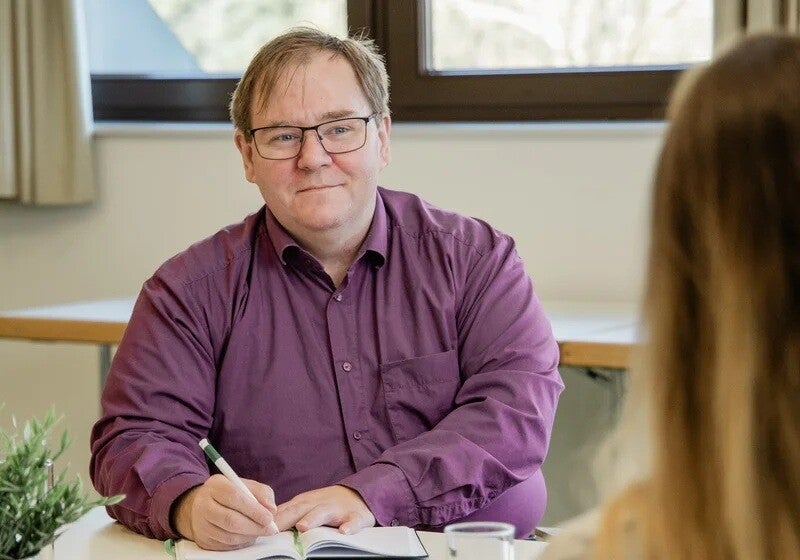 Ronald Neumayer im Beratungsgespräch mit einer Klientin am Tisch.