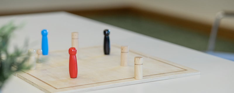Holzfiguren auf einem Arbeitsbrett als Material zur Klärung von Rollen und Zusammenarbeit