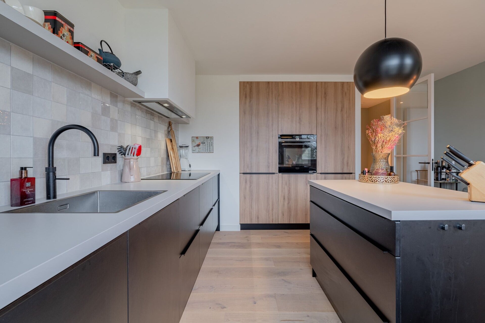 zwarte woonkeuken met hoge kasten in houtkleur