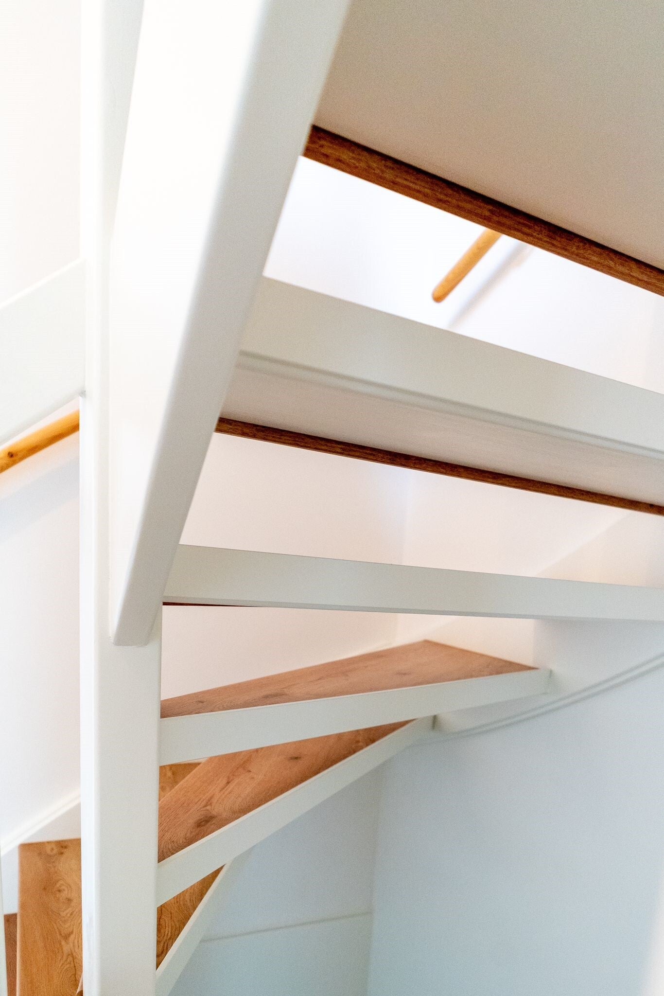 achterzijde van een witte open trap met houten overzettreden 