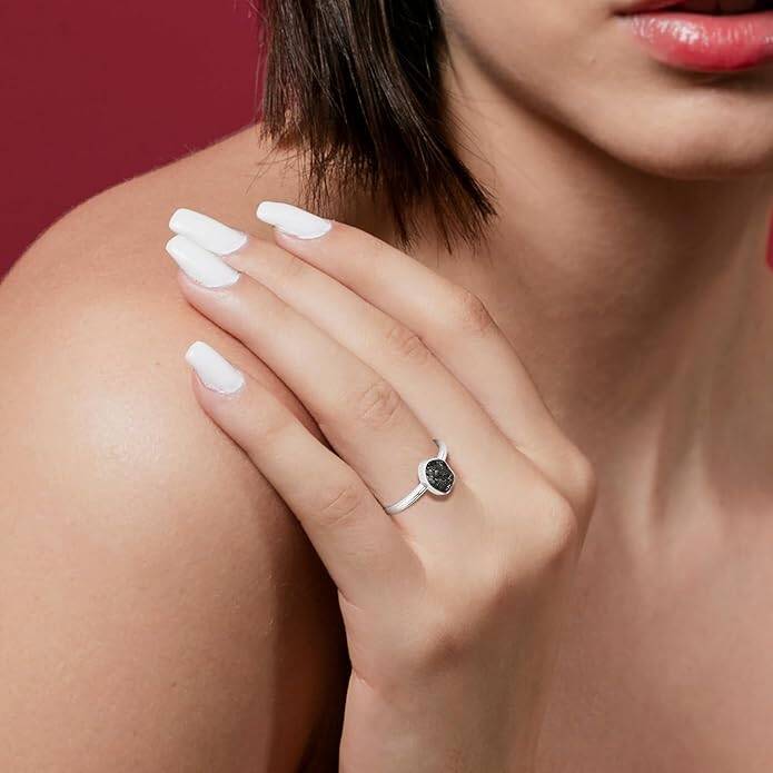A woman confidently displays a raw black tourmaline stackable ring on her hand, symbolizing spiritual protection and divine empowerment.