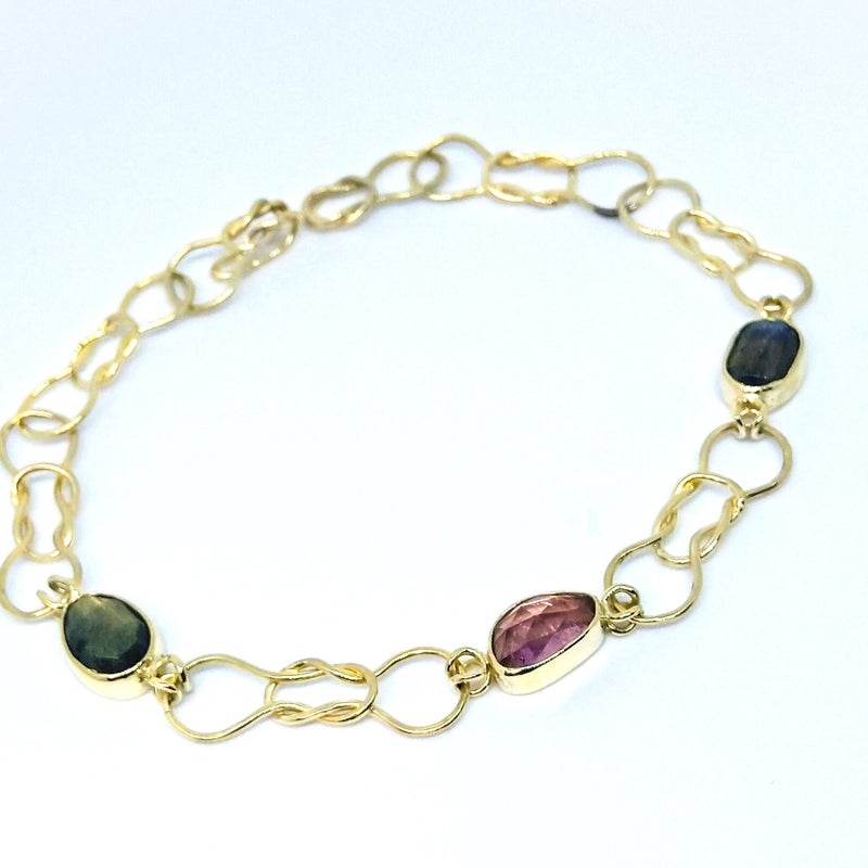 Topstuk. Geelgouden schakelarmband met grote d'Or elastiek schakels met rosecut labradoriet, saffier en labradoriet. Prijs vanaf € 1675,-