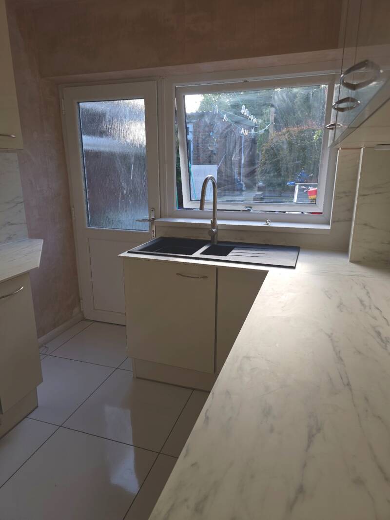 Professional kitchen fitting in Cardiff featuring integrated appliances and contemporary cream cabinets