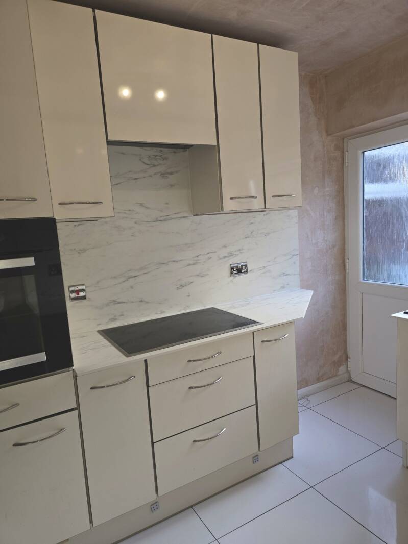 Modern cream gloss kitchen installation in Cardiff with marble-effect worktops and splashbacks