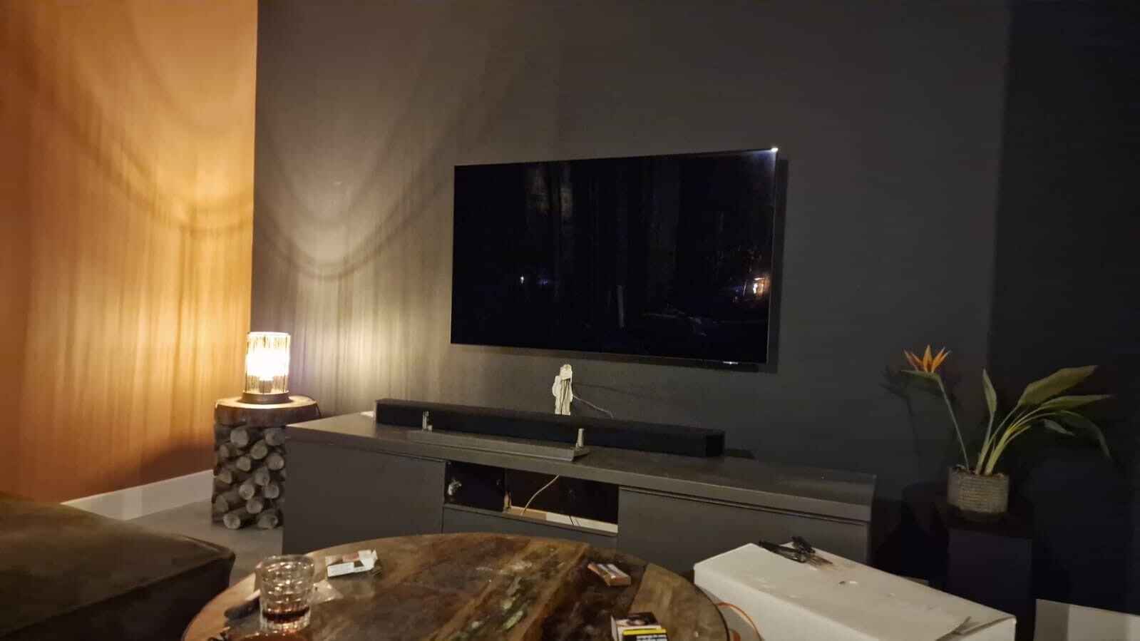 Woonkamer met warme houten wand en donkere accentkleur