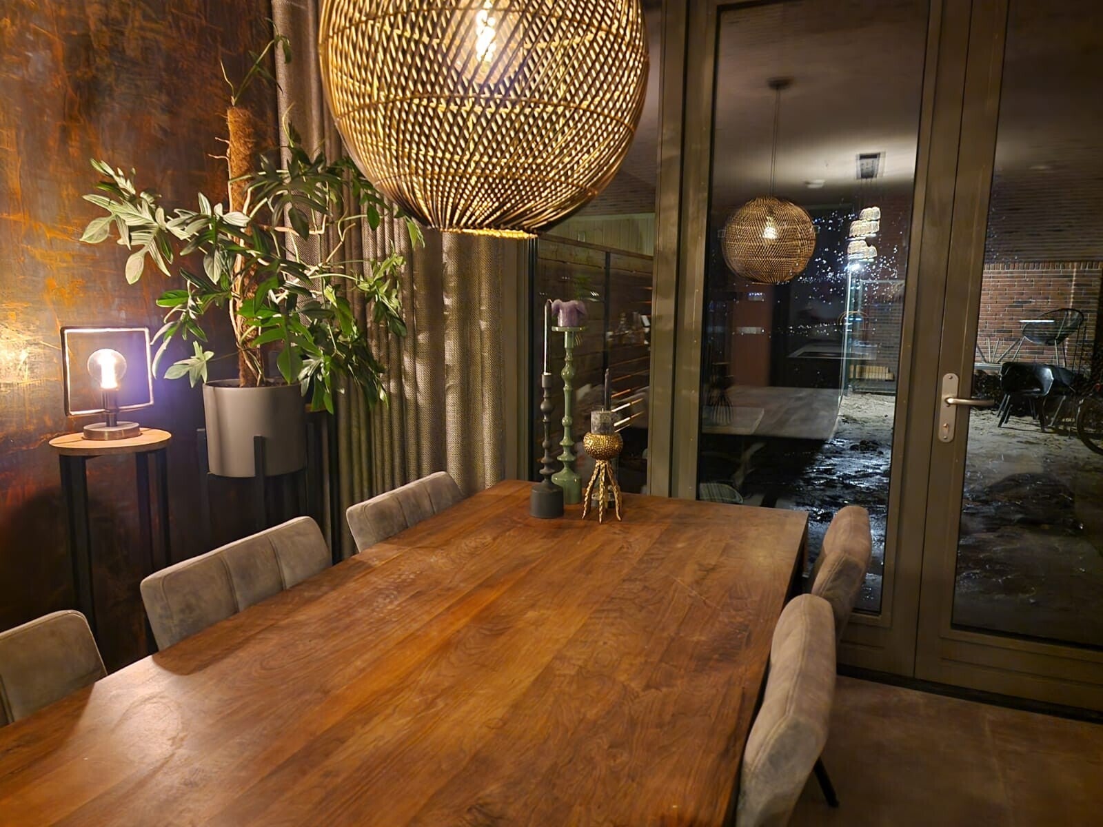 Warm interieur met houten eettafel, verlichting en rijke wandbekleding