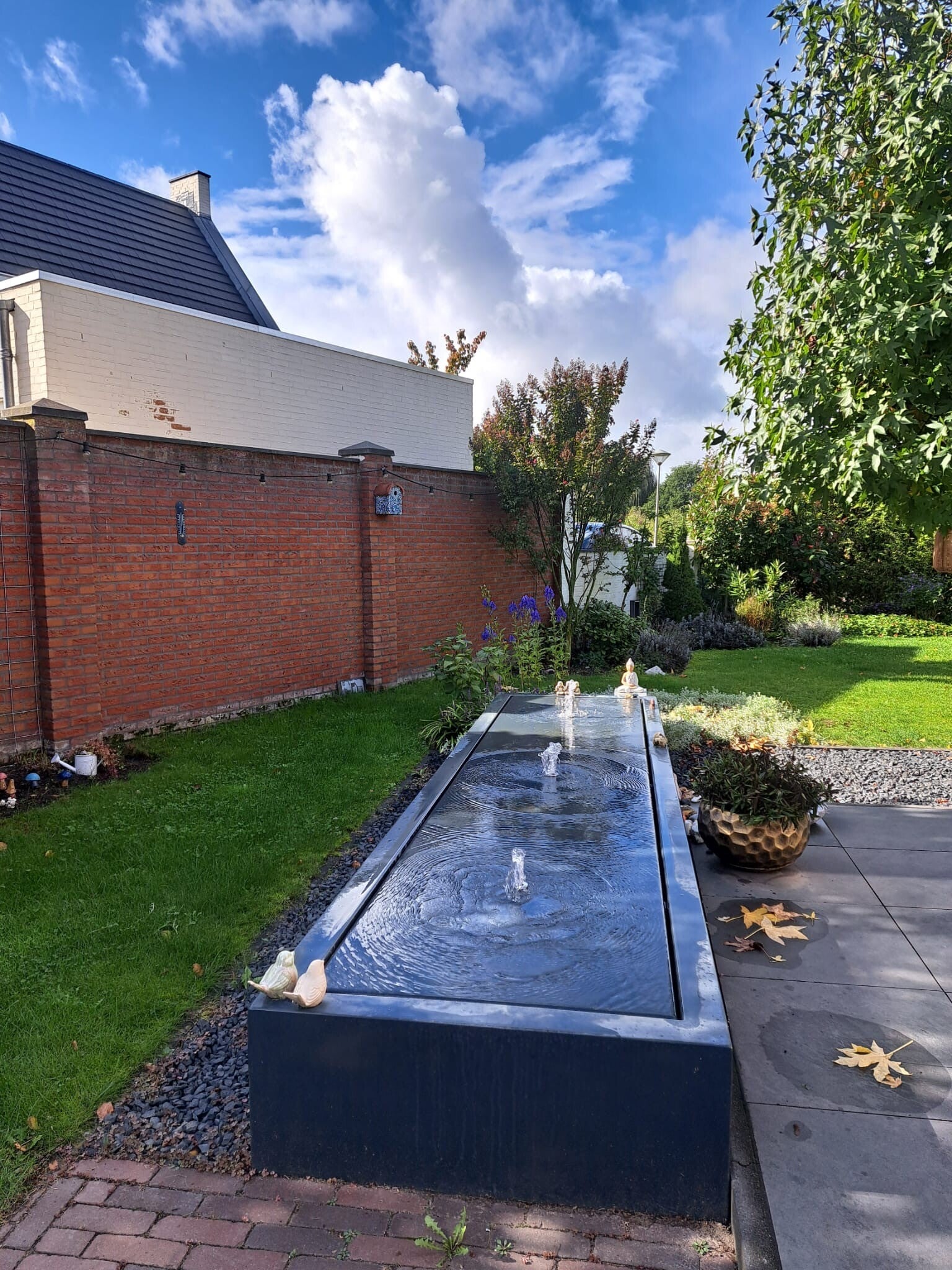 Tuin bij de praktijk in Herpen met groen en een langwerpig waterornament