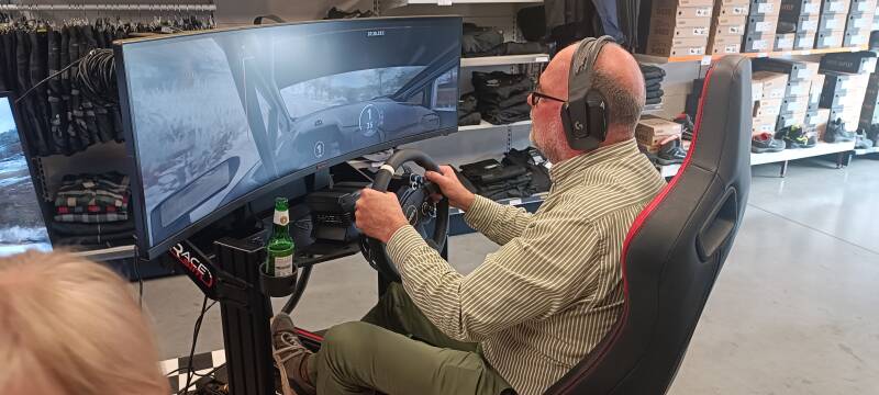 Deelnemer racet op een race simulator van RACE-SIM tijdens een autosportactie bij Comtex in Roeselare