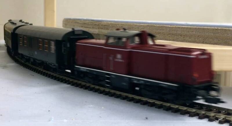 Locomotief van de Baureihe 210 komt met twee  personenrijtuigen aan gereden.