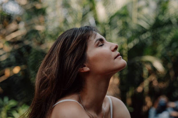 Woman in nature with closed eyes, breathing in a relaxed state