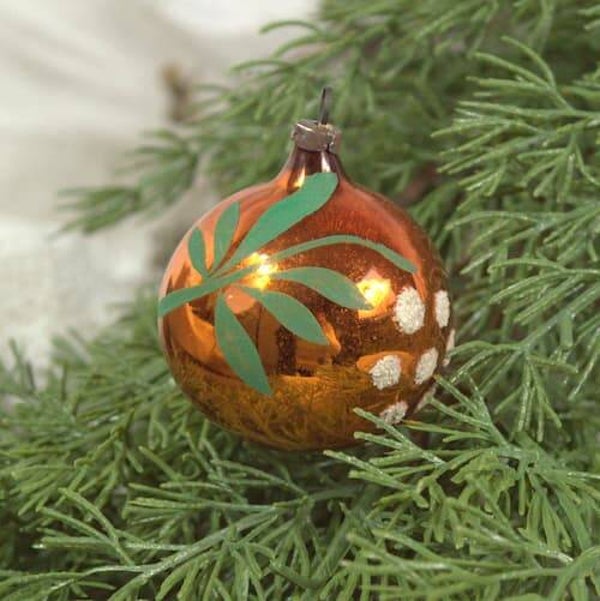 Vintage goudkleurig kerstballetje met takje in wit en groen als decoratie