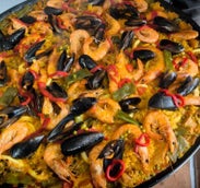 paella affiché dans la casserole, avec des crevettes, moules, fruits de mer, pâtes, riz, viande de poulet, végétarienne, pour tous les goûts. suisse, neuchâtel, sur place ou à l'emporter, mariage anniversaire, amis, repas d'entreprises