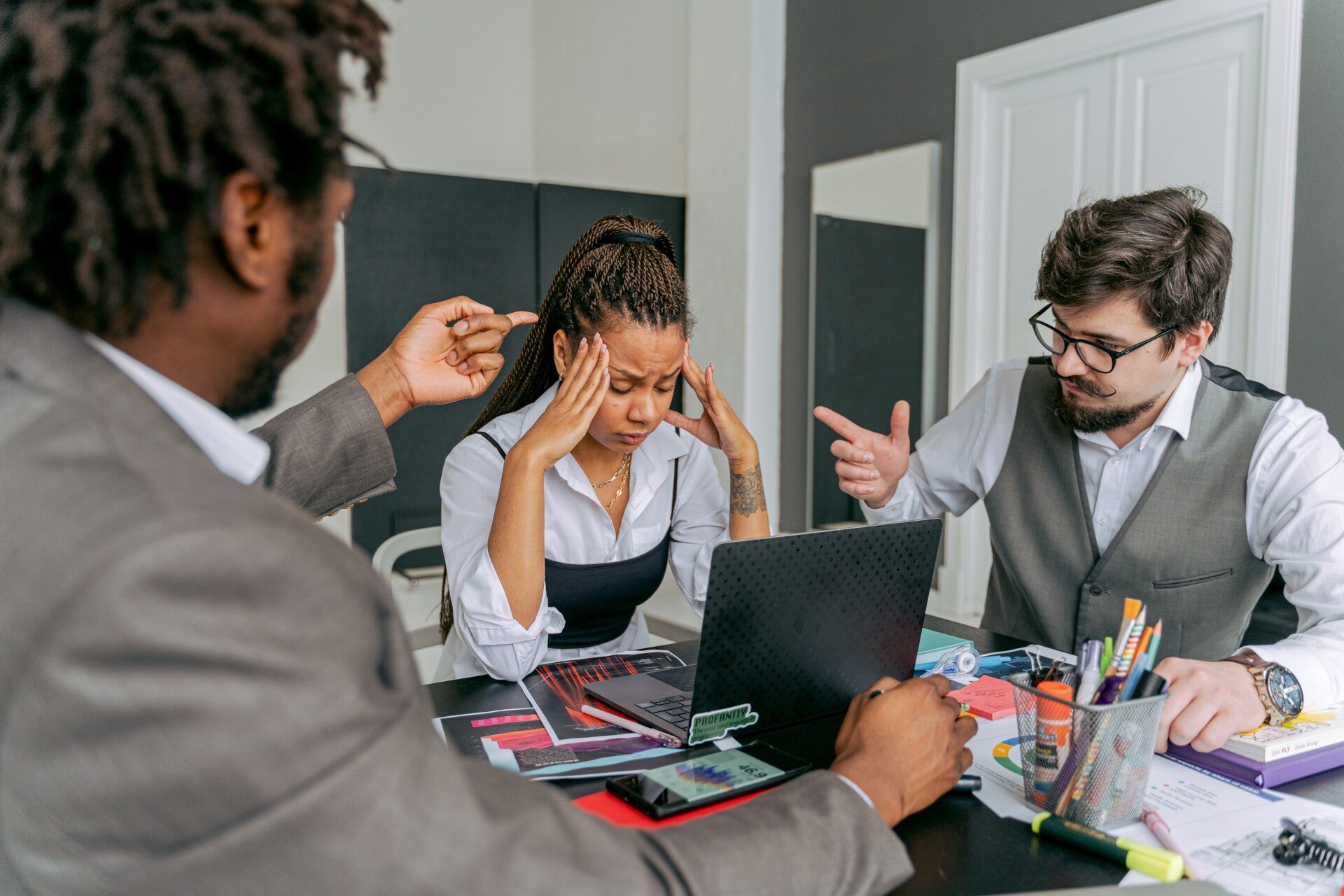 Salariée en situation de stress au travail, entourée de deux collègues, illustration des risques psychosociaux