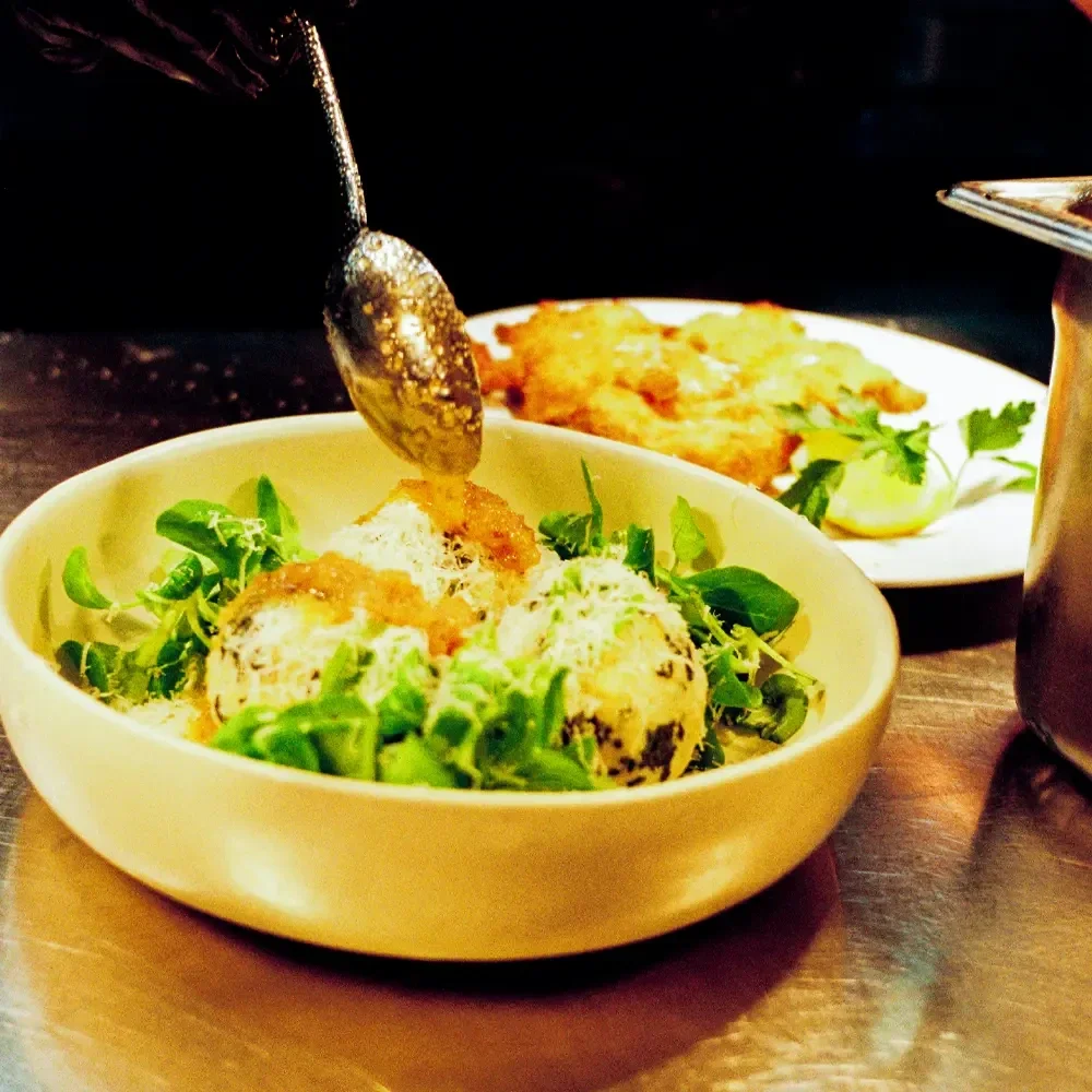 Spinatknödel im Schneeweiß Berlin, serviert mit feiner Sauce und alpiner Handschrift.