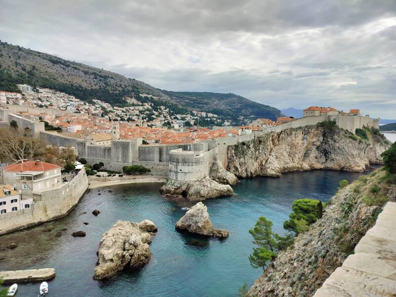 Historic stone walls and fortresses of Dubrovnik’s Old Town rising above the Adriatic, with rocky cliffs and calm sea below.
