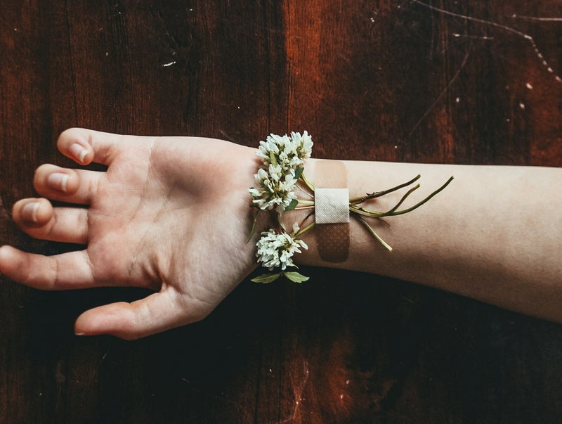 Een pleister met bloemen op een pols - symbool voor zichtbaar en onzichtbaar ziek zijn, omgaan met ziekte, chronisch ziek zijn