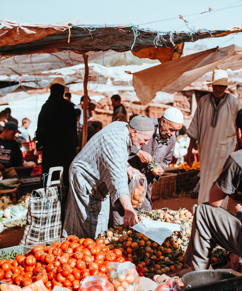 "Local Moroccan men buying fresh fruits and vegetables at a traditional souk – immerse yourself in authentic Moroccan culture with our private cultural tours and local market experiences"