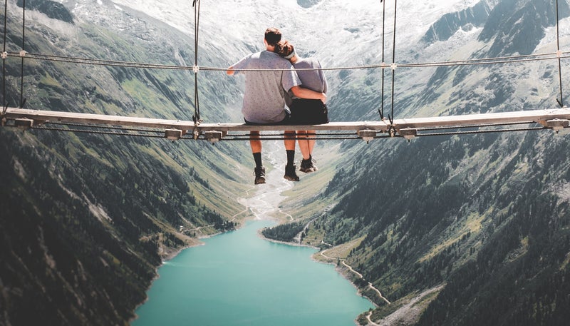 Gemeinsame Erlebnisse schweißen zusammen und schaffen bleibende Erinnerungen: Ein Paar steht an einem See und beobachtet gemeinsam den Sonnenuntergang.