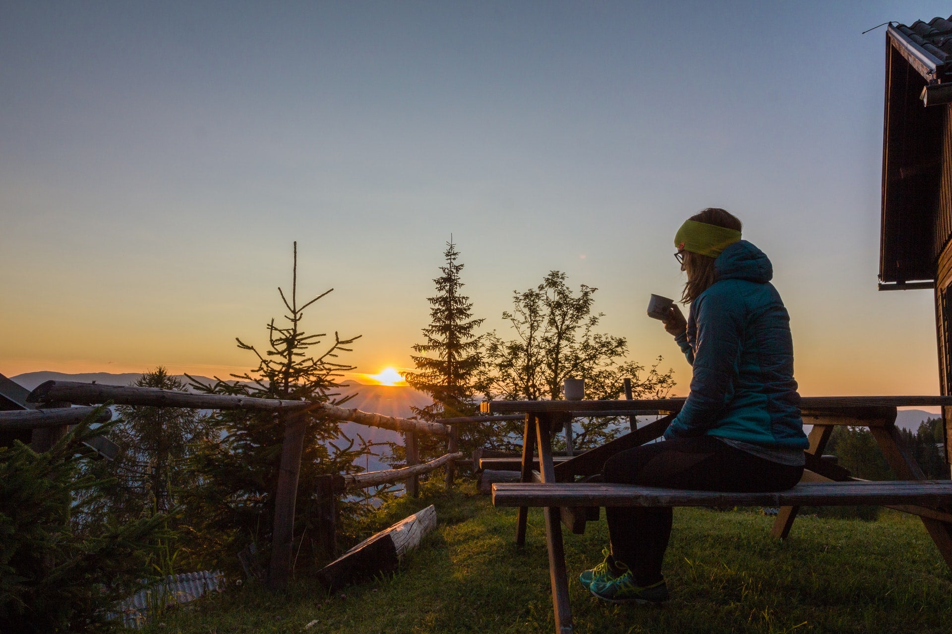 Peaceful woman watching a golden sunset over the ocean horizon, finding a moment of spiritual gratitude.